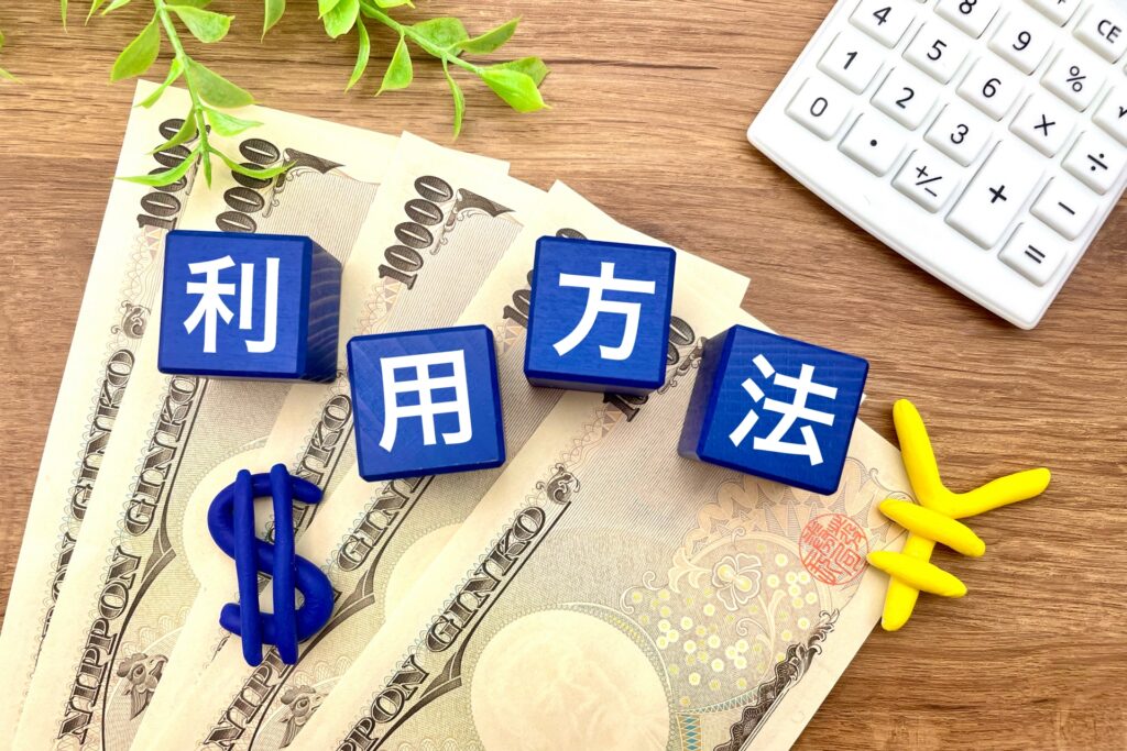 木目調の机の上にお札があり、その上に「利用方法」と書かれたサイコロがある