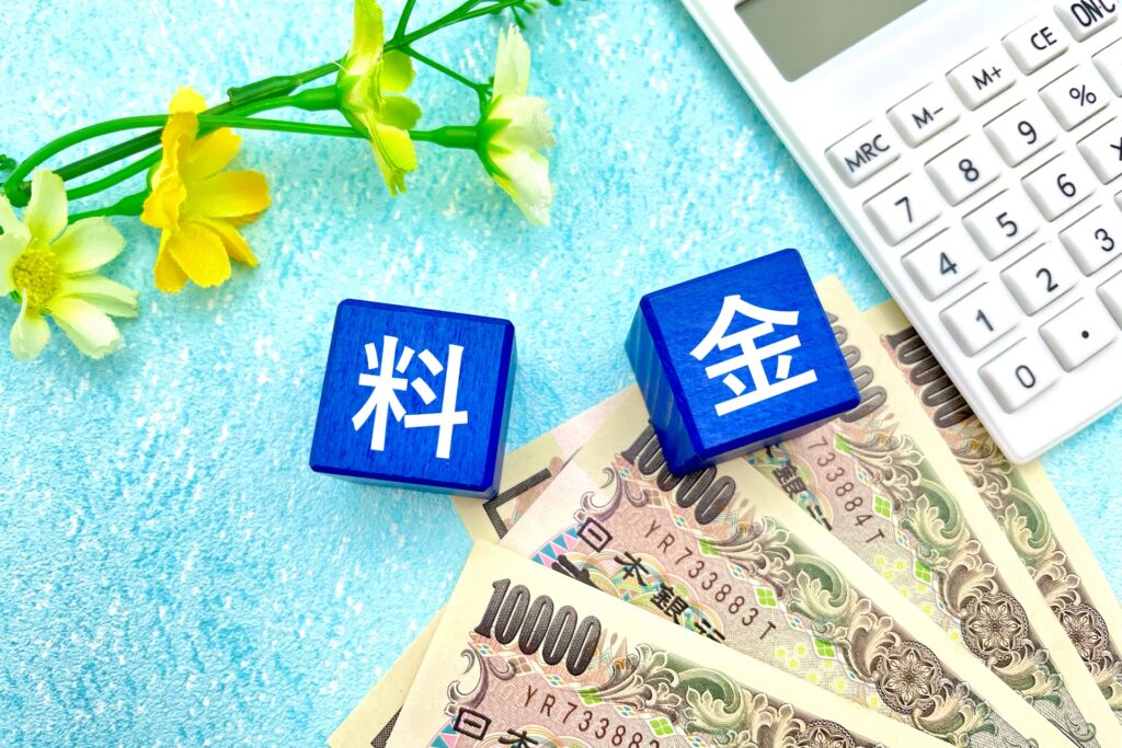 水色の布の上に4枚のお札、黄色い花、電卓と、料金と書かれたサイコロがある