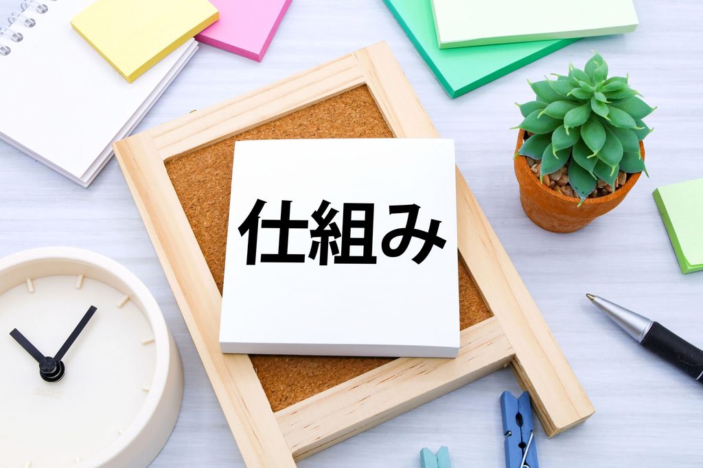 イーゼルの上に仕組みと書かれた白い板が乗っている
