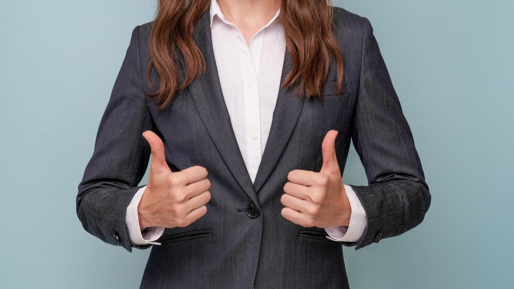 ビジネススーツの女性がグッドポーズをとっている