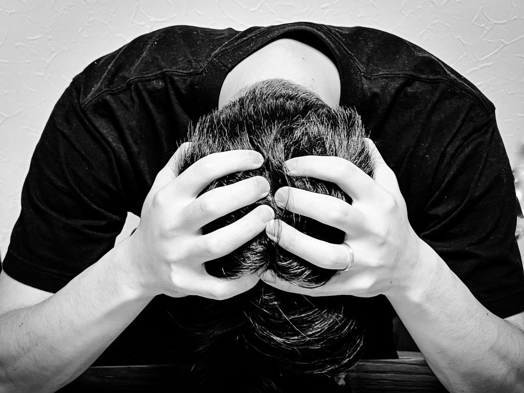 頭を抱えて悩みこむ男性